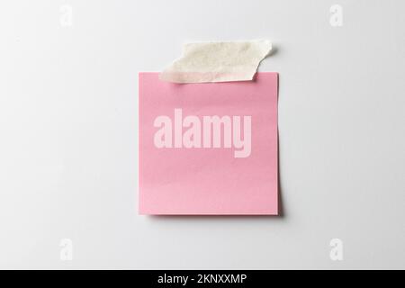 Pink sticky memo note with tape and copy space on white background Stock Photo