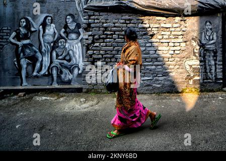 Kolkata, India. 26th Nov, 2022. A woman walks past graffiti mural artwork on a wall. Kolkata Streets and different slums seen getting painted with colorful graffiti as an initiative by a Football Club (Milan Sangha) in Kolkata. Artists from different Art colleges have participated to make the city more beautiful. Credit: SOPA Images Limited/Alamy Live News Stock Photo