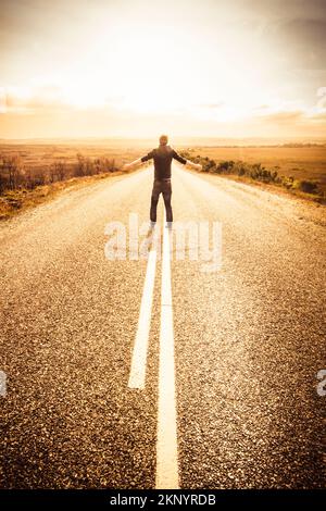 Creative freedom concept of a risk taking travelling tourist stopping traffic with arms raised in the middle of the road. Taken Granville Harbour, Tas Stock Photo