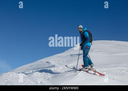 An active ski-tour rider on a winter trail in the middle of the mountain range. Winter mountains landscape outdoor concept Stock Photo