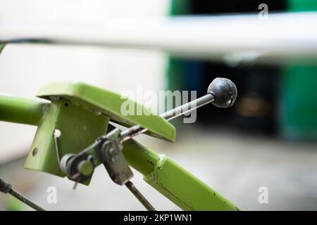 The control lever on a walk-behind tractor close-up on a blurred background. Control elements of agricultural machinery. Stock Photo