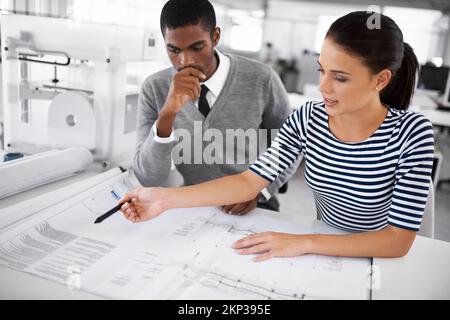 Checking every little detail. two designers going over blueprints. Stock Photo