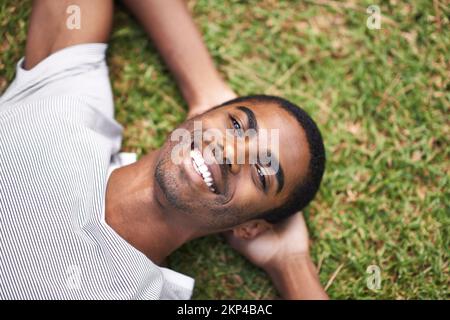 Making the best of his break. a handsome young man lying on the grass outdoors. Stock Photo