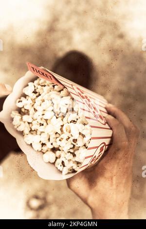 Top down view on a vintage audience member holding a box of buttered popcorn with ticket. Movie nostalgia Stock Photo