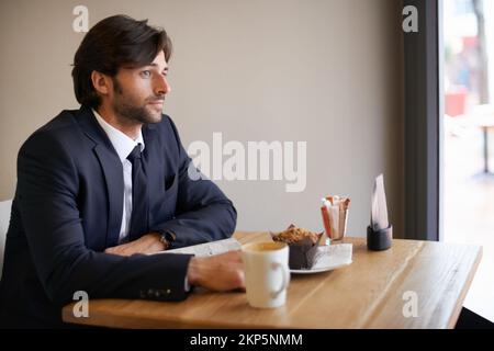 Hes a regular here. A thoughtful businessman sitting in a coffee shop and looking out of the window. Stock Photo