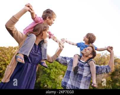 Spending the day together. a young mother and father carrying their sons on their shoulders. Stock Photo
