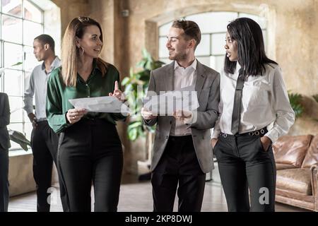 Office multiethnic co-workers discussing about a project standing together in the office hall - informal business people lifestyle concept Stock Photo