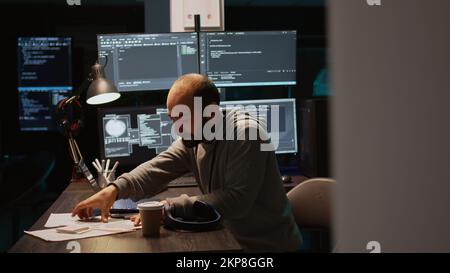 Young programmer typing server code on multiple monitors, displaying terminal window with html language. Programming cloud computing interface on laptop to develop system. Handheld shot. Stock Photo