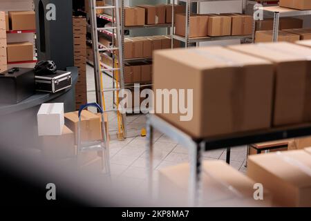 Empty huge distribution storehouse equipped with high shelves fill with carton boxes, online orders ready for delivering. Interior of new large and modern warehouse space with nobody in it Stock Photo