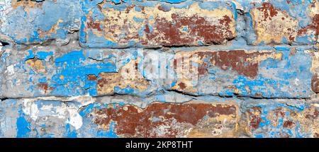 weathered brick wall with peeling blue and white paint Stock Photo