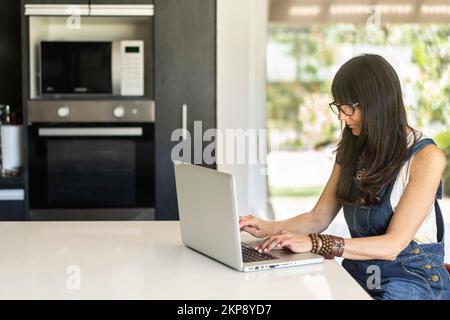 Business woman working from home while looking at laptop. Confident woman using laptop Stock Photo