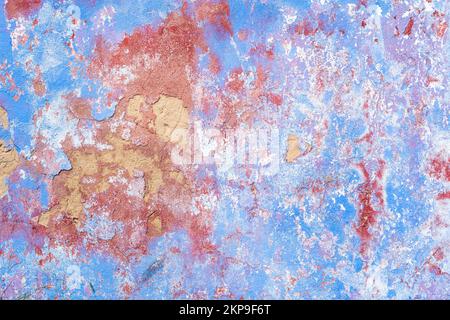 Old painted plaster wall outside, paint in many colours peeling off aged building exterior background. Stock Photo