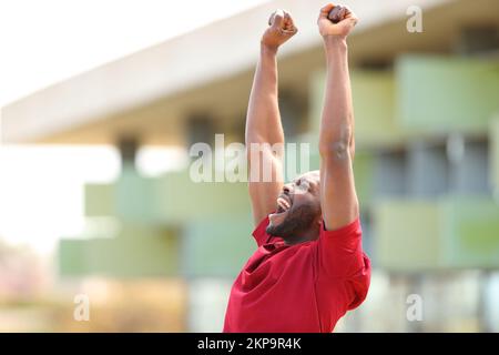 Excited black man in red raising arms celebraing success in the street Stock Photo