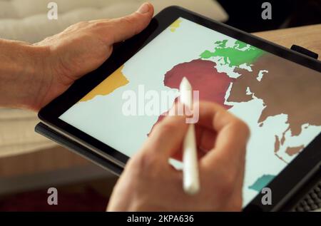 Close up of a pan pointing on a a world map on a tablet Stock Photo