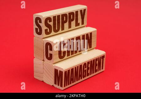 Business and economy concept. On a red background, wooden blocks with the inscription - Supply Chain Management Stock Photo