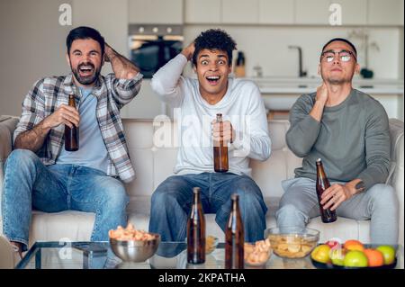 Company of pals viewing a television together Stock Photo