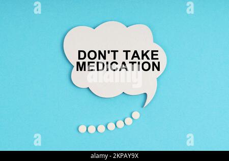 Medicine and health concept. On a blue table are pills and a white plate with the inscription - Don t take medication Stock Photo