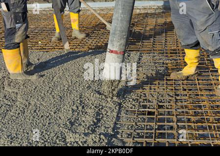 Construction worker pours concrete on rebar using concrete pump Stock Photo