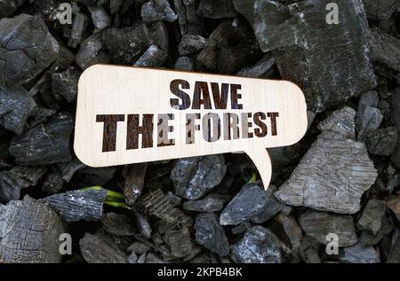 Ecology and industry concept. There is a wooden plaque on the charcoal with the inscription - Save the forest Stock Photo