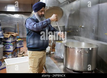 A cook in the Golden Temple cooks in an extremely large pot.