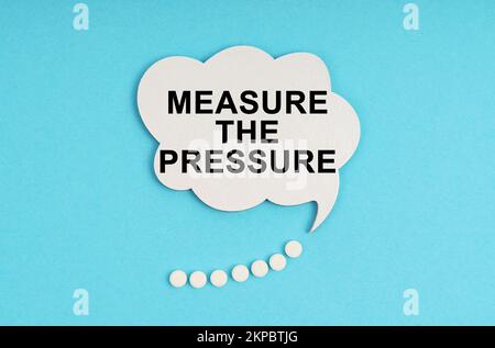 Medicine and health concept. On a blue table are pills and a white plate with the inscription - Measure the pressure Stock Photo