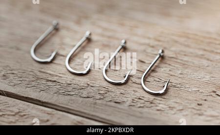 Fishing hooks on a wooden board. Close-up of a fishing hook. Blurred concept Stock Photo