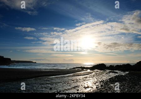 Setting sun over the ocean at Gunwalloe, Cornwall, UK - John Gollop Stock Photo