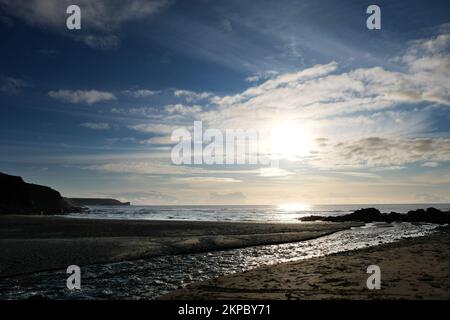 Setting sun over the ocean at Gunwalloe, Cornwall, UK - John Gollop Stock Photo