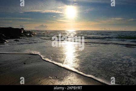 Setting sun over the ocean at Gunwalloe, Cornwall, UK - John Gollop Stock Photo