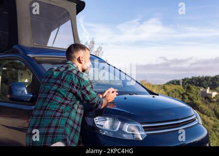 man leaning on his camper van observing nature Stock Photo
