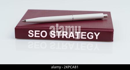 Business and finance concept. On a white surface lies a pen and a notebook with the inscription - SEO STRATEGY Stock Photo