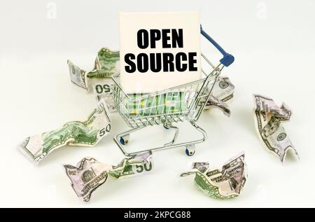 Business and economy concept. Crumpled dollars lie on a white surface, there is a cart inside a sign with the inscription - OPEN SOURCE Stock Photo