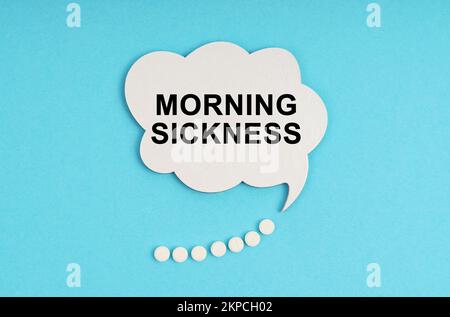 Medicine and health concept. On a blue table are pills and a white plate with the inscription - MORNING SICKNESS Stock Photo