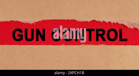 Law concept. Among the torn sheets of paper on a red background, the inscription - Gun Control Stock Photo