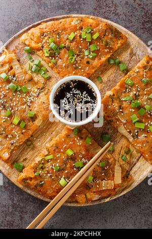 Korean Pancakes Kimchijeon is basically made with kimchi and a little scallions closeup on the wooden board on the table. Vertical top view from above Stock Photo