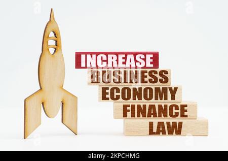 Business and finance concept. On the white surface there is a wooden rocket and planks, on the red plaque the inscription - INCREASE Stock Photo