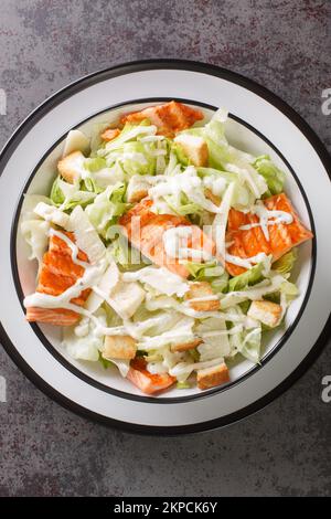 Salmon Caesar Salad it features easy homemade dressing, freshly baked croutons, parmesan and grilled salmon closeup on the plate on the table. Vertica Stock Photo