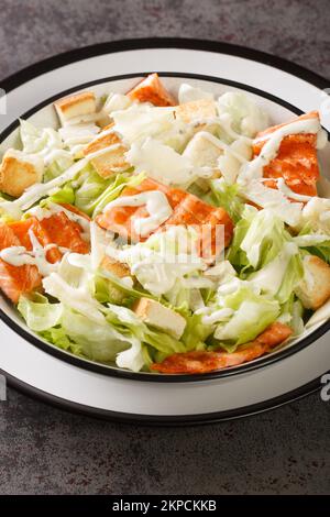 Delicious light salmon caesar salad with fresh croutons, lettuce and grilled fish close-up in a plate on the table. Vertical Stock Photo