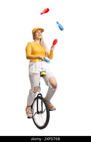 Young female riding a mono cycle and juggling isolated on white background Stock Photo
