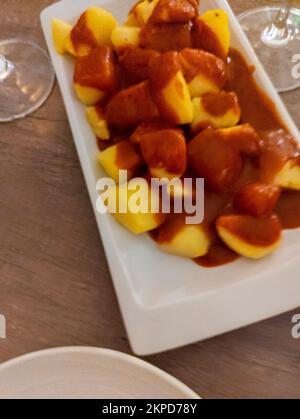 Typical Spanish dish called patatas bravas, fried tubers with red spicy sauce containing onion, paprika, oregano, chilli Stock Photo