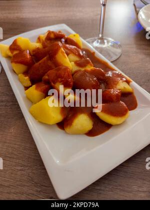 Typical Spanish dish called patatas bravas, fried tubers with red spicy sauce containing onion, paprika, oregano, chilli Stock Photo