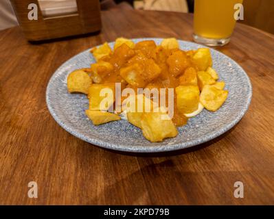 Typical Spanish dish called patatas bravas, fried tubers with red spicy sauce containing onion, paprika, oregano, chilli Stock Photo