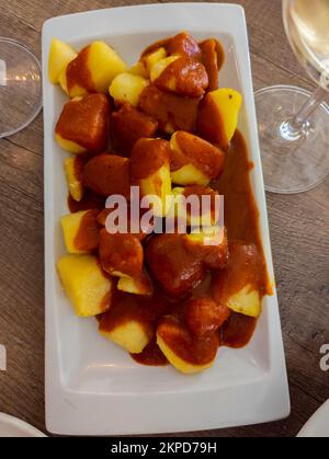 Typical Spanish dish called patatas bravas, fried tubers with red spicy sauce containing onion, paprika, oregano, chilli Stock Photo