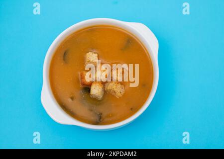 vegetable soup with crackers in white bowl on blue paper Stock Photo