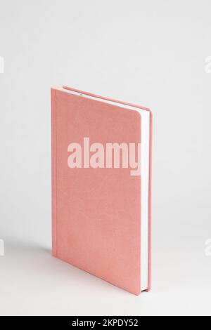 Pink diary standing on table on white background. Side view Stock Photo