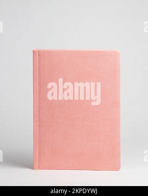 Pink diary standing on table on white background. Front side Stock Photo