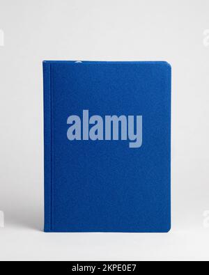 A blue closed diary standing on a table on a white background. Front view Stock Photo