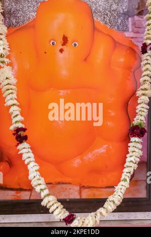 hindu god ganesha idol worshiped with flowers vertical shot from flat angle image is taken at ganesh temple ratanada jodhpur rajasthan india. Stock Photo