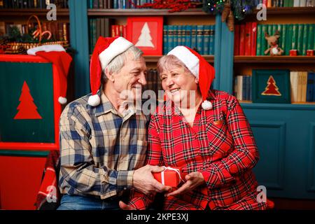 Photo of Happy senior couple exchanging Christmas presents at home. Stock Photo