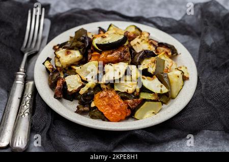 Mixed baked vegetables on light brown dish on ceramic Stock Photo